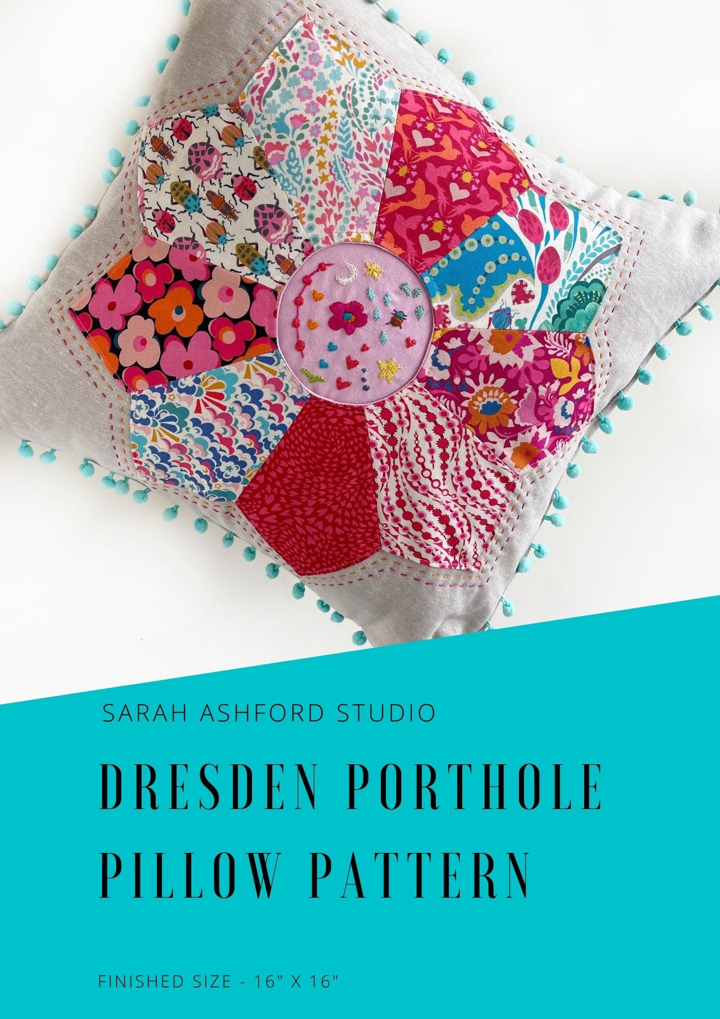 Sewing pattern. A cushion being held at an angle with beautiful embroidered detail in the centre and a floral patchwork design. There are pom poms around the edge of the cushion.