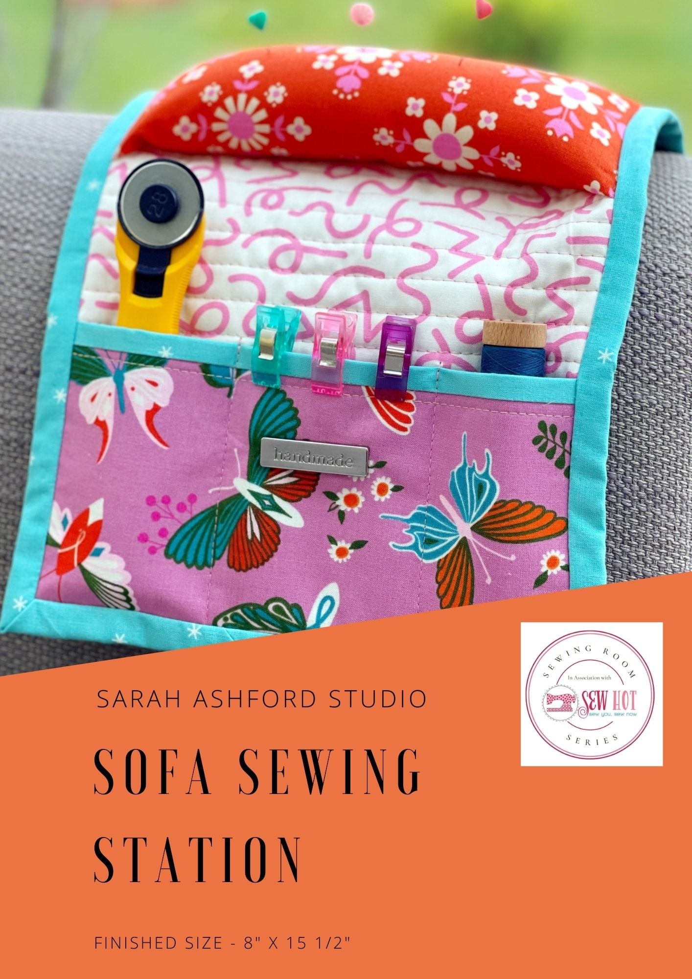 Sewing pattern. This sofa sewing station sits over the arm of a sofa. There is a pincushion in the middle, and a series of pockets, holding a small rotary cutter, binding clips and thread. There is a 'handmade' silver tag on the pocket.