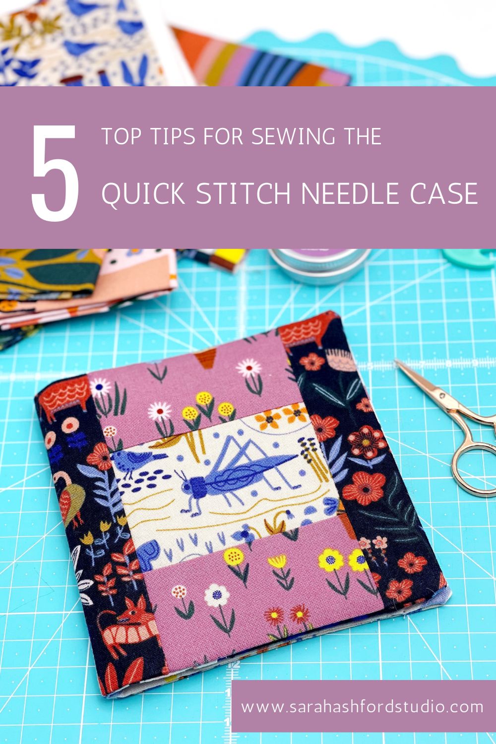 Open needle case on a cutting mat, containing thread, needles, pins and embroidery scissors.  