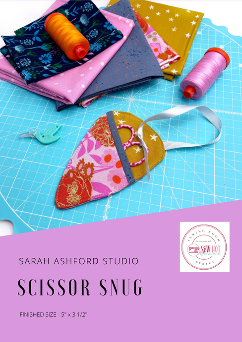 Sewing pattern. A little scissor case, just big enough to hold a pair of embroidery scissors sits on a cutting mat with some matching fabrics and threads.  Pink scissors sit inside the case, attached to the case with a white ribbon. 